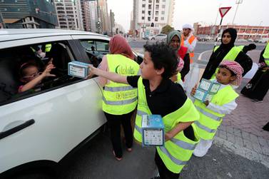 Ramadan Aman participant Iyad hands an iftar box to a passenger near Al Wahda Mall in Abu Dhabi. Pawan Singh / The National 