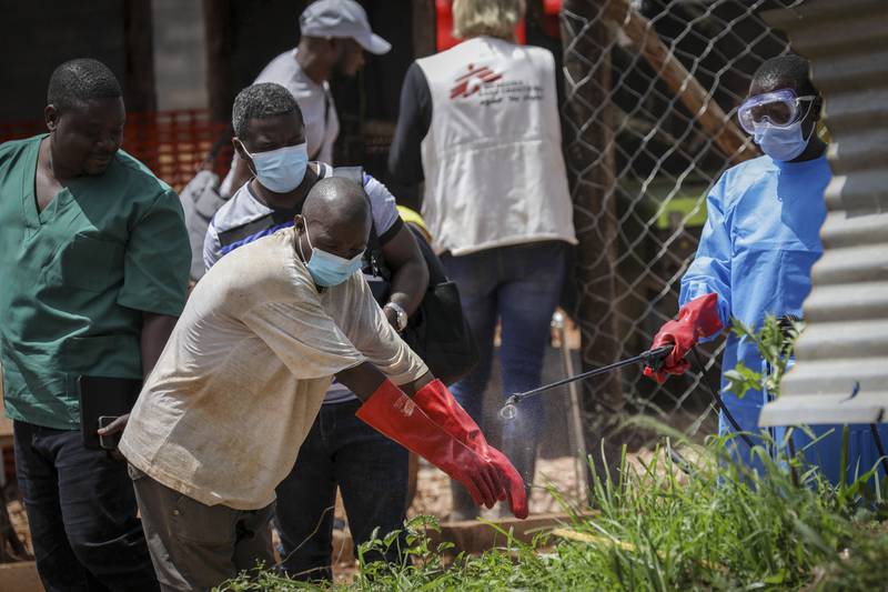 A medical attendant disinfects a man's gloves before leaving the Ebola isolation section of Mubende Regional Referral Hospital. AP
