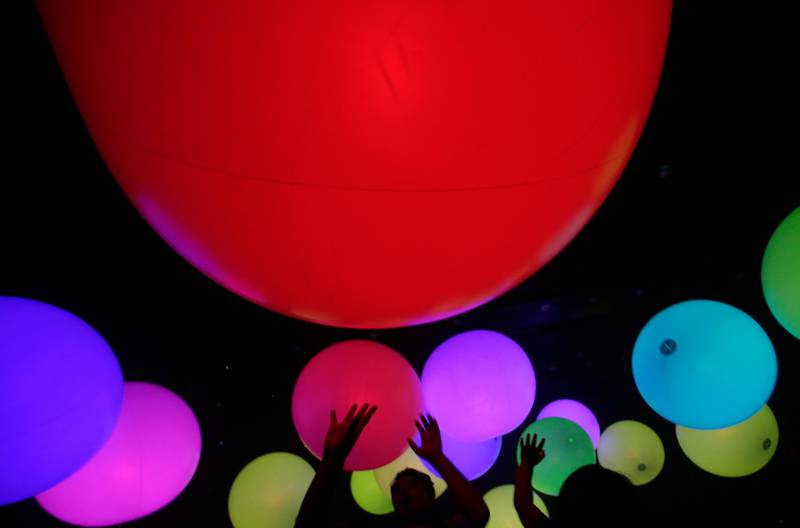 Visitors at the Jungle and Future Park in Tokyo reach out to touch colourful balloons known as "sound spheres" in an art and interactive music installation by teamLab. Shizuo Kambayashi / AP Photo
