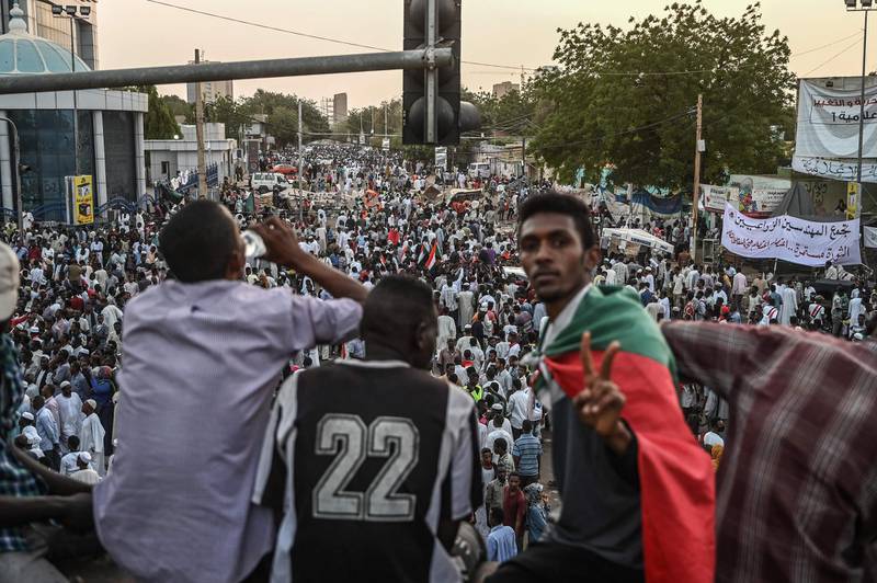 Sudanese protesters gestures as they sit on a bridge during a protest outside the army headquarters in the capital Khartoum on April 19, 2019.  Protest leaders on April 19, 2019 announced plans to unveil a civilian ruling body to replace the current transitional military council as crowds of demonstrators kept up the pressure outside army headquarters and Washington said it will send an envoy to encourage the transition.  / AFP / OZAN KOSE
