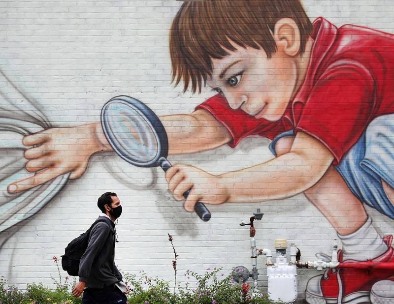 Johnny Lopez makes his way past a mural on the side of Hideaway Pizza on Rockford Ave. while walking home from work in Tulsa, Oklahoma, USA. Tulsa World via AP