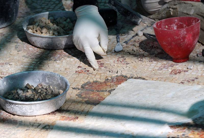 A worker selects pieces to restore a mosaic at the ancient Byzantine church complex. AFP