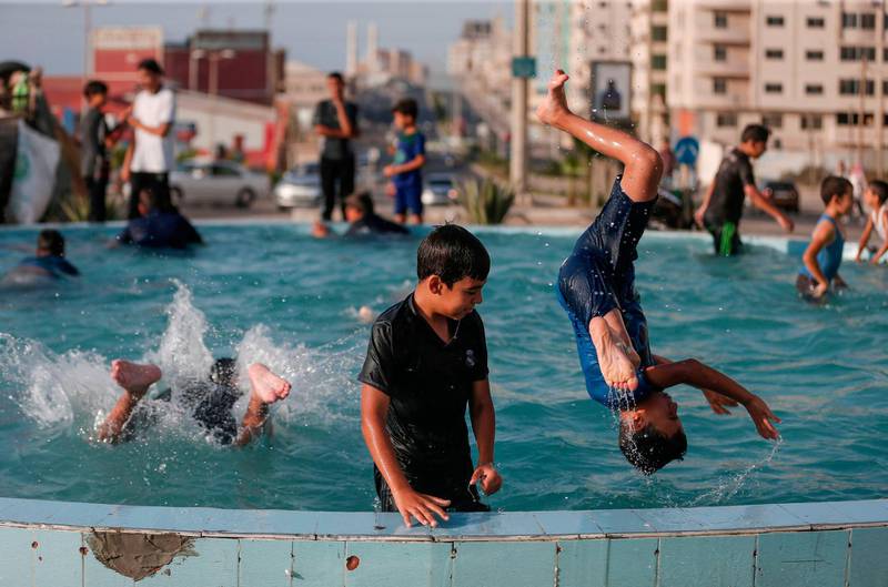 Children play in a public fountain during a hot summer day in Gaza City. AFP