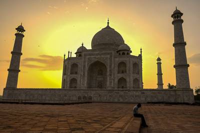 A security guard takes a break as the sun rises behind the Taj Mahal after it reopened to visitors. AFP