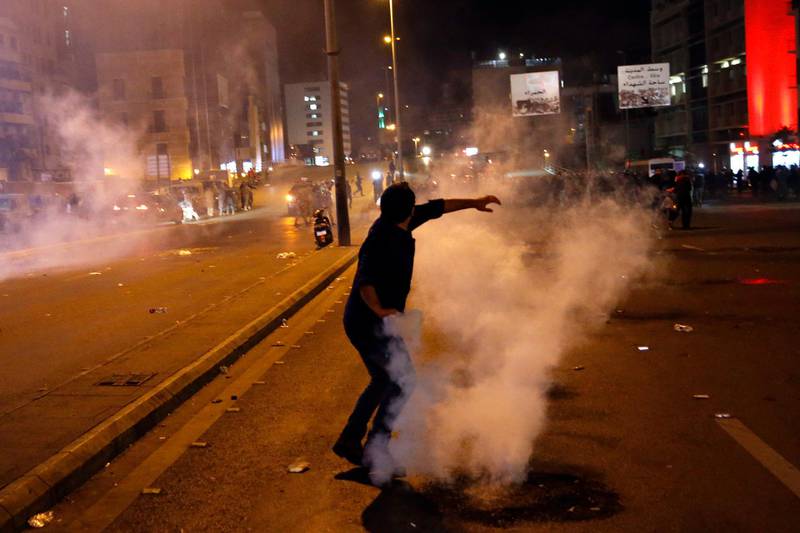 A protester throws back a tear gas canister that was fired towards them by Lebanese riot police during an anti-government protest in Beirut, Lebanon. AP Photo