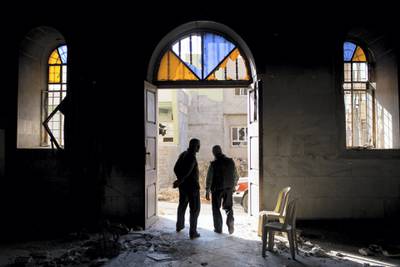QARAQOSH, IRAQ - NOVEMBER 08:  Two men are seen surveying the burnt and destroyed interior of the St Mary al-Tahira church on November 8, 2016 in Qaraqosh, Iraq. The NPU is a military organization made up of Assyrian Christians and was formed in late 2014 to defend against ISIL. Qaraqosh, a largely Assyrian City just 32km southeast of Mosul was taken by ISIL in August, 2014 forcing all residents to flee, the town was largely destroyed with all of the churches burned or heavily damaged. The town stayed under ISIL control last week when it was liberated during the Mosul Offensive.  (Photo by Chris McGrath/Getty Images)