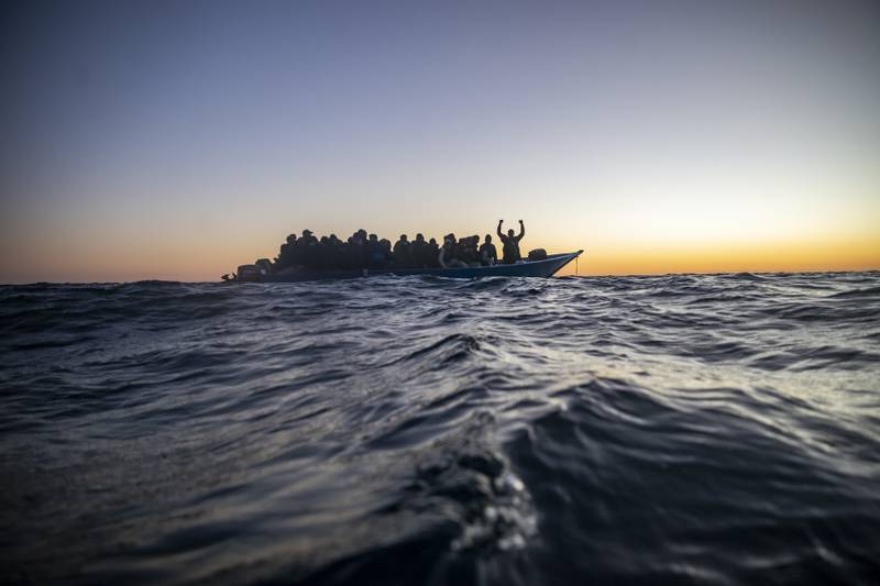 Migrants wait for assistance aboard an overcrowded wooden boat, 122 miles off the coast of Libya. AP