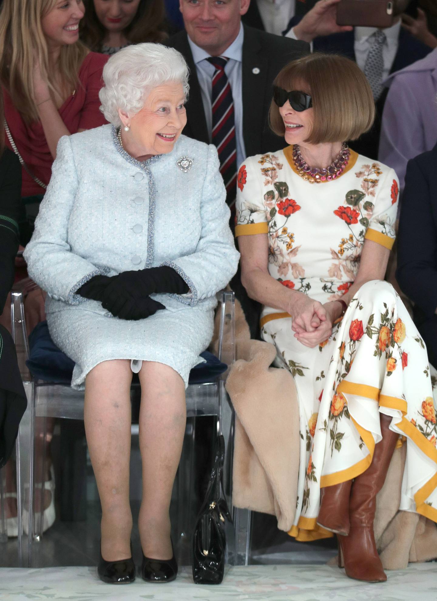 Queen Elizabeth II, wearing an Angela Kelly tweed dress and jacket in duck egg blue, embellished with tiny aquamarine Swarovski crystals, next to Anna Wintour at the Richard Quinn show, as part of London Fashion Week in 2018. AFP