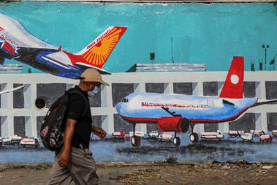 A pedestrian walks past a mural of aircraft at an airport, in Mumbai, India, on Wednesday, May 26, 2021. India is preparing a stimulus package for sectors worst affected by a deadly coronavirus wave, aiming to support an economy struggling with a slew of localized lockdowns, people familiar with the matter said. The finance ministry is working on proposals to bolster the tourism, aviation and hospitality industries, along with small and medium-sized companies. Photographer: Dhiraj Singh/Bloomberg
