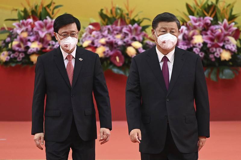 The city's new leader, John Lee, left, walks off the stage with Mr Xi after the swearing-in ceremony. AP