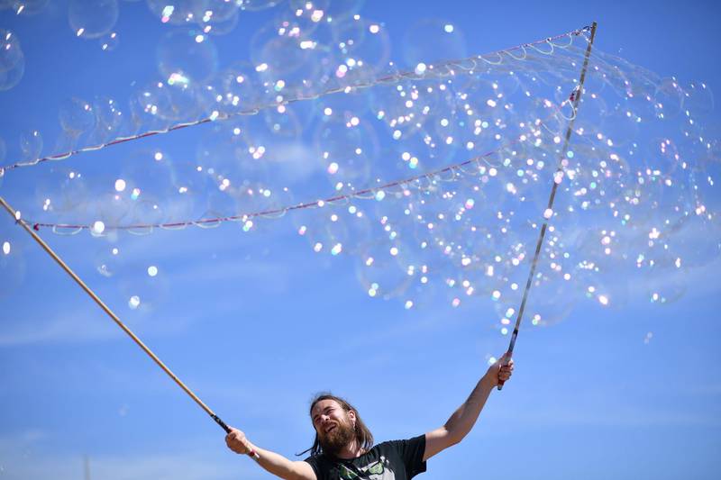 A man entertains the public with bubble tricks in the sunshine on the beach in Brighton, on the south coast of England. AFP