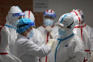 Medical staff write messages on their protective suits before attending to coronavirus patients in Wuhan. AFP