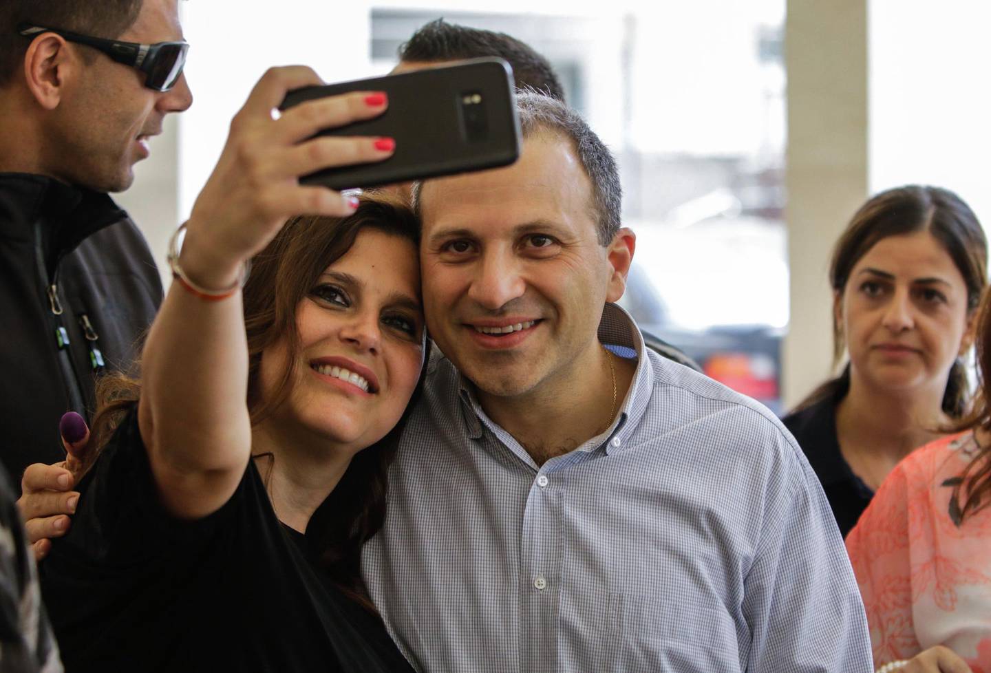 Gibran Bassil (C), the Lebanese Foreign Minister and leader of the "Free Patriotic Movement", poses for a "selfie" photograph with his wife Chantal as he arrives to cast his vote at a polling station in the Lebanese coastal city of Batroun, north of the capital Beirut, on May 6, 2018, as the country votes in the first parliamentary election in nine years.
Polling stations opened at 7:00 am across the small country, which has an electorate of around 3.7 million, and were due to close 12 hours later, with results from all 15 districts expected the following day. / AFP PHOTO / IBRAHIM CHALHOUB