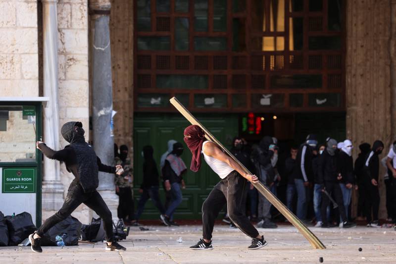 Palestinian youths hurl stones towards police at a gate to Al Aqsa Mosque compound. Reuters