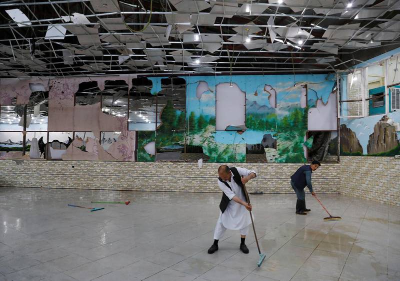 Men clean a damaged wedding hall after a blast in Kabul. Reuters
