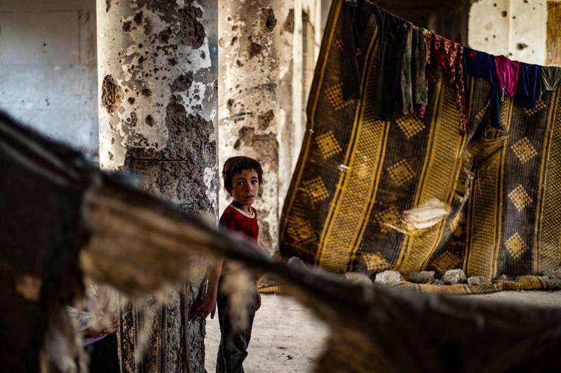 A Syrian boy, displaced with his family from Deir Ezzor, looks at the camera inside the damaged building where he is living in Syria's northern city of Raqqa.