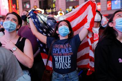 Gabriella Ziccarelli, 32, from Arizona, holds a US flag as she watches a speech by vice president-elect Kamala Harris, in Times Square in New York City. Reuters