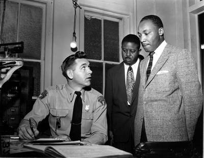 King, right, accompanied by the Rev Ralph D Abernathy, centre, is booked by city police Lt  D H  Lackey in Montgomery, Alabama, for his part in the bus boycott protests, on February 23, 1956. AP