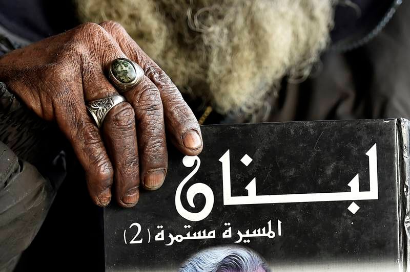 Mohammed Maghrabi holds a book that reads 'Lebanon' in Arabic.