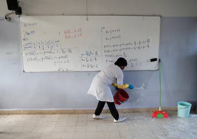 A worker splashes disinfectant in a classroom as part of sterilisation campaign against the new coronavirus, at the Evangelical School, in Loueizeh, east of Beirut, Lebanon. AP Photo
