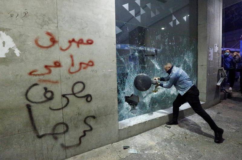 SENSITIVE MATERIAL. THIS IMAGE MAY OFFEND OR DISTURB An anti-bank message is seen on a wall as a protester smashes the window of a bank, as demonstrations against the economic crisis continue in Beirut, Lebanon January 14, 2020. REUTERS/Mohamed Azakir TPX IMAGES OF THE DAY