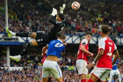 Arsenal's goalkeeper David Raya, top, blocks Everton's James Tarkowski's shot. AP