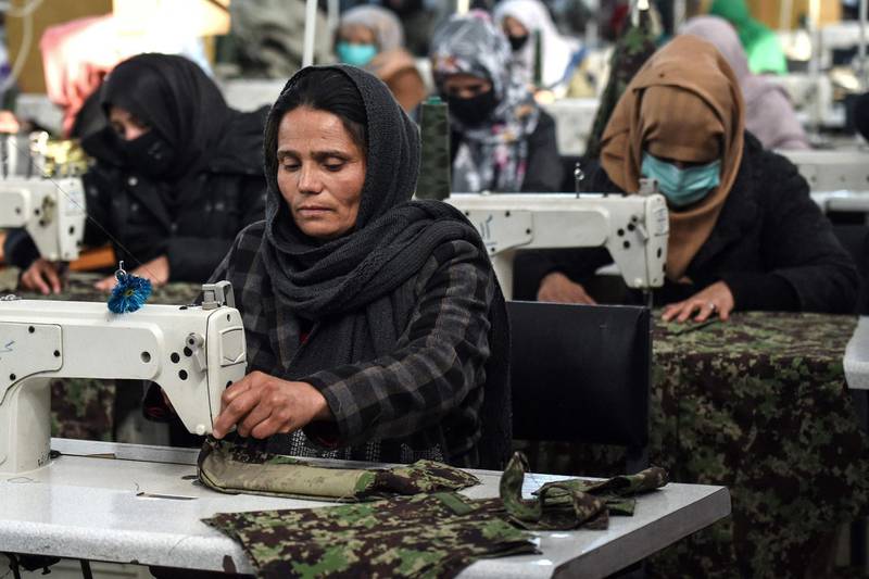 In this photograph taken on February 8, 2021, women who lost their husband or relatives in the ongoing war in Afghanistan with the Taliban stitch military uniforms at a factory in Kabul. Dozens of women widowed by the Afghan war have been given a lifeline by the army, stitching military uniforms indistinguishable from the ones their husbands died in. / AFP / WAKIL KOHSAR
