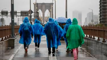 People walk across the Brooklyn Bridge in the heavy rain in New York. EPA