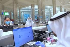 An immigration official checks a passenger's documents at Dubai International Airport. Wam