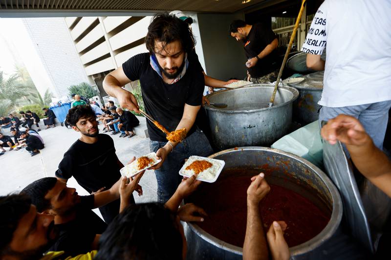 Iraqi men distribute free meals for supporters of Mr Al Sadr during the parliament building sit-in.. Reuters