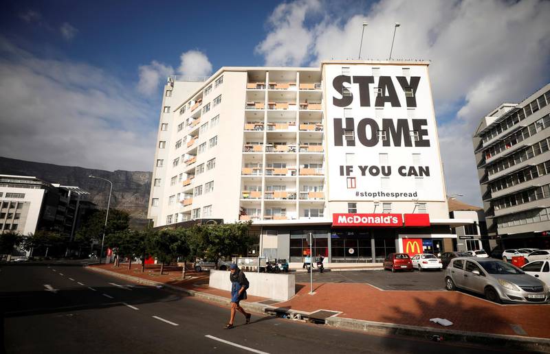 A man walks past a poster covering the side of a building ahead of a 21 day lockdown aimed at limiting the spread of coronavirus disease (COVID-19), in Cape Town, South Africa, March 26, 2020. REUTERS/Mike Hutchings