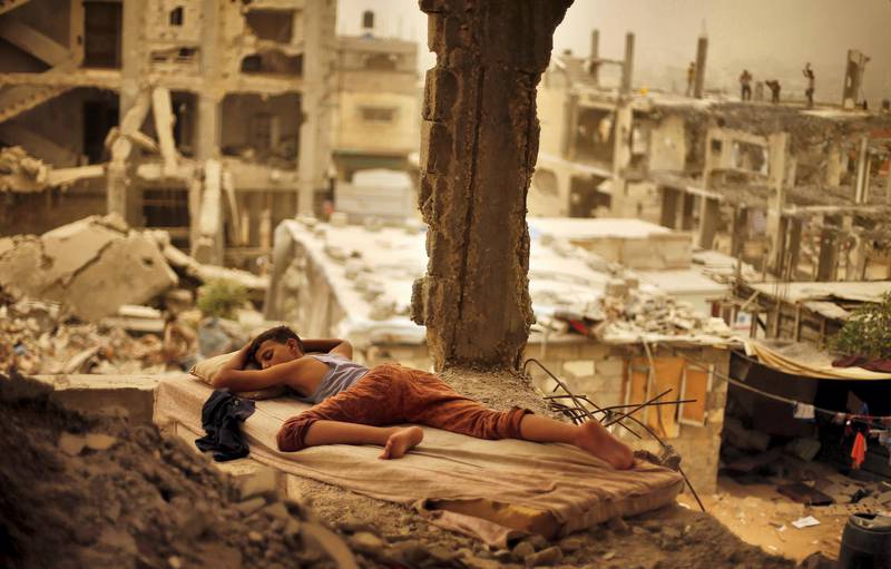 A Palestinian boy sleeps on a mattress inside the remains of his family's house, that witnesses said was destroyed by Israeli shelling during a 50-day war in 2014 summer, during a sandstorm in Gaza September 8, 2015. A heavy sandstorm swept across parts of the Middle East on Tuesday, killing two people and hospitalising hundreds in Lebanon and disrupting fighting and air strikes in neighbouring Syria. Clouds of dust also engulfed Israel, Jordan and Cyprus where aircraft were diverted to Paphos from Larnaca airport as visibility fell to 500 metres. REUTERS/Suhaib Salem      TPX IMAGES OF THE DAY