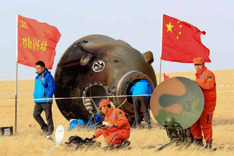 In this photo released by Xinhua News Agency, ground crew check on the re-entry capsule of Shenzhou 11 spacecraft after it landed in north China's Inner Mongolia Autonomous Region, Friday, Nov. 18, 2016. A pair of Chinese astronauts returned Friday from a monthlong stay aboard the country's space station, China's sixth and longest crewed mission and a sign of the growing ambitions of its rapidly advancing space program. (Li Gang/Xinhua via AP)