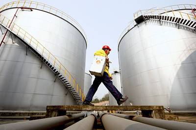FILE - In this Thursday, Jan. 28, 2010 file photo, a worker walks past tanks at a Petrochina storage base in Suining, in southwest China's Sichuan province. A big shift is happening in Big Oil: an American giant now ranks second to a Chinese upstart. Exxon Mobil is pumping less oil than PetroChina, a company formed just 13 years ago by the Chinese government to better compete for the world's oil and natural gas. On March 29, 2012, the shift is expected to become official when the Beijing company announces that it produced more crude last year than its 130-year-old Texas rival. (AP Photo) *** Local Caption ***  CORRECTION Big Oil New No 1.JPEG-0d101.jpg