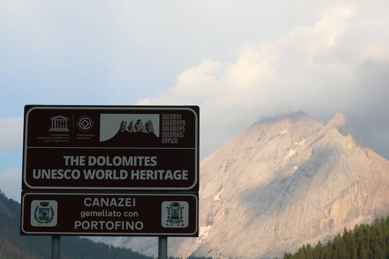 This photograph taken on July 3, 2022 from Canazei, shows a UNESCO World Heritage sign of The Dolomites, near the Marmolada mountain and glacier, where the collapse of an ice serac killed six people.  - An avalanche set off by the collapse of the largest glacier in the Italian Alps killed at least six people and injured eight others on July 3, 2022, an emergency services spokeswoman said.  The glacier collapsed on the mountain of Marmolada, the highest in the Italian Dolomites, near the hamlet of Punta Rocca, on the route normally taken to reach its summit.  (Photo by Pierre TEYSSOT  /  AFP)