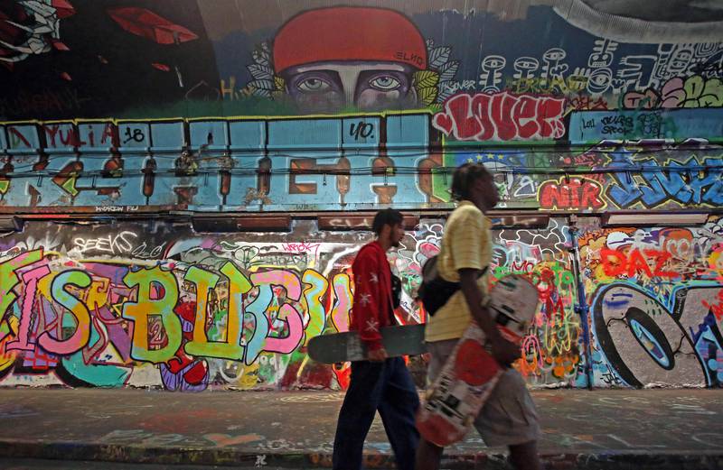 Skateboarders walk past the graffiti in Leake Street graffiti tunnel in London. AFP