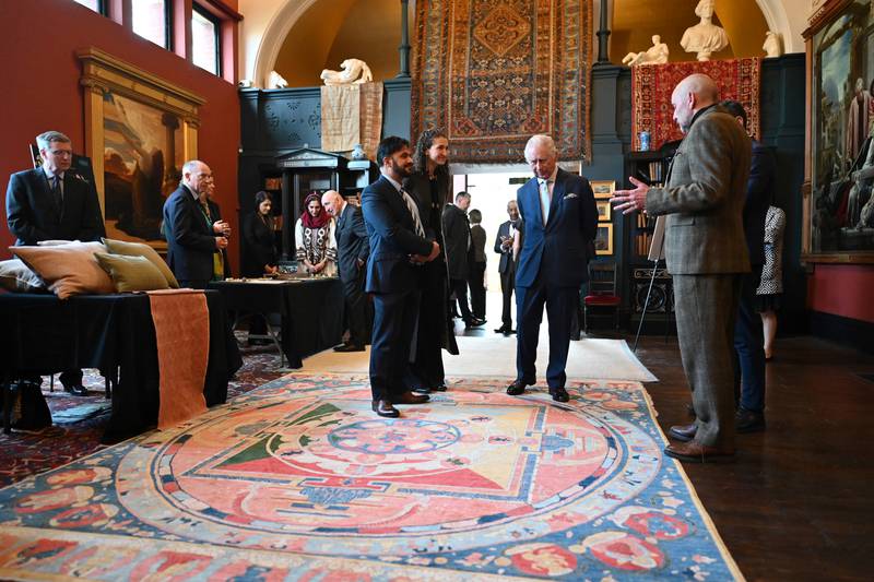 Britain's King Charles III learns about weaving while looking at rugs made in Afghanistan at the newly renovated museum Leighton House, to see art pieces commissioned by the association Turquoise Mountain. Photo: Justin Tallis/ WPA Pool/Getty Images