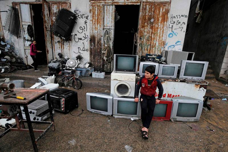 A Palestinian boy sits on TV sets for sale at a shop for used appliances in Gaza City.  AFP