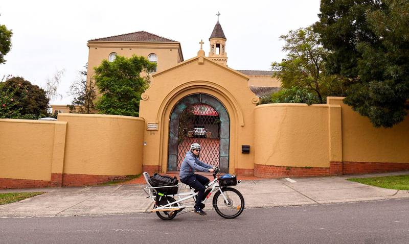 A man cycles past the Carmelite Monastery in Melbourne on April 7, 2020, where Cardinal George Pell is staying after been released from Barwon Prison earlier in the day. Pell left jail a free man on April 7 after Australia's High Court quashed his child sex abuse convictions. / AFP / William WEST
