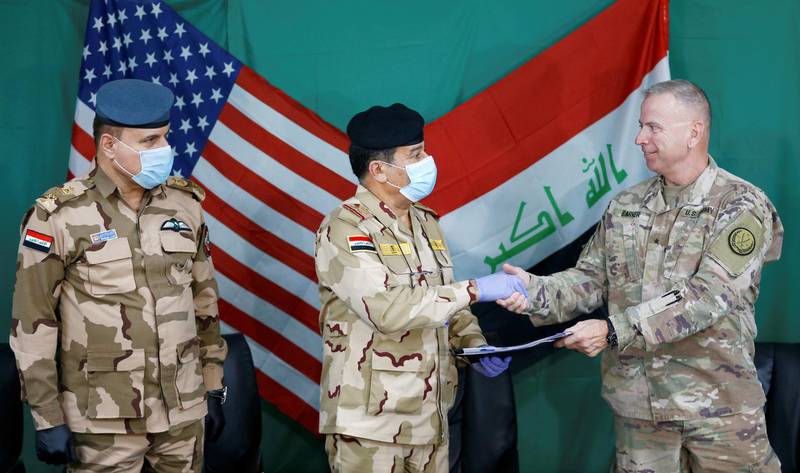FILE PHOTO: U.S. Brigadier General Vincent Barker (R) shakes hands with Iraqi General Mohammed Fadel (C), wearing face mask and gloves, following the outbreak of coronvavirus disease (COVID-19), during the hand over of Qayyarah Airfield West from US-led coalition forces to Iraqi Security Forces, in the south of Mosul, Iraq March 26, 2020.    REUTERS/Thaier Al-Sudani/File Photo. To match Special Report IRAQ-IRAN/MOSUL