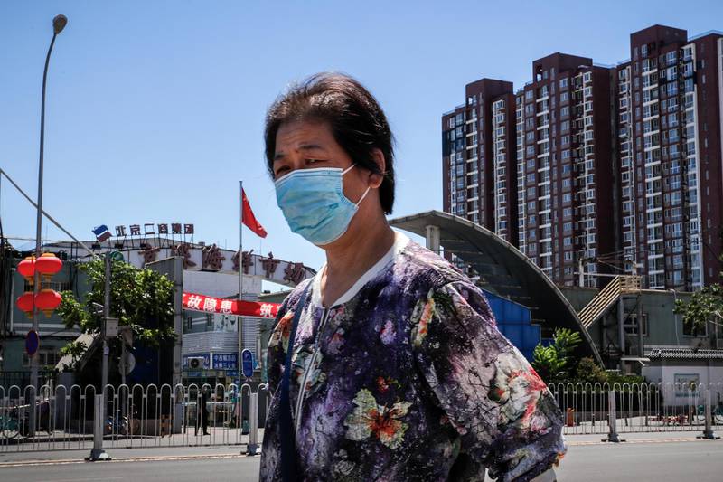 A woman wearing a protective face mask walks by the seafood wholesale market closed for inspection in Beijing. AP Photo