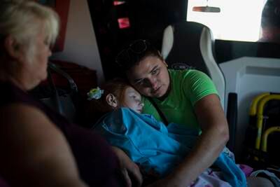 A Ukrainian woman holds her daughter in the back of an ambulance operated by Red Cross volunteers in Kupyansk, Kharkiv region. AP