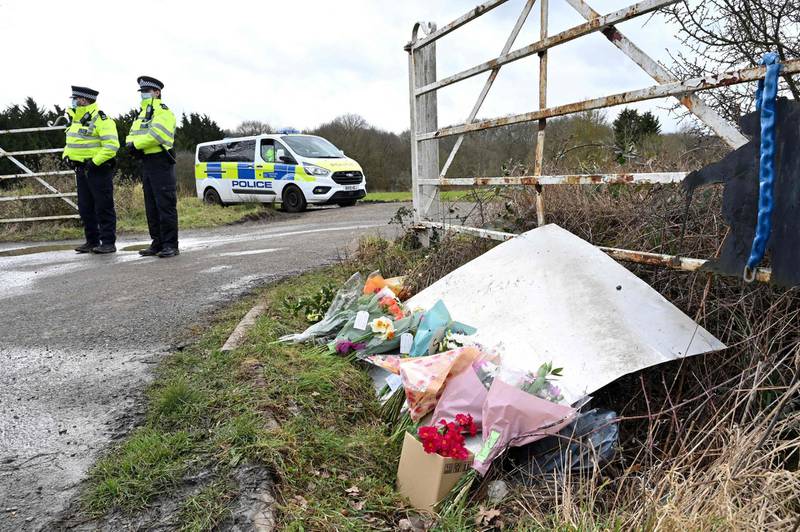 Flowers and messages of condolence for Sarah Everard are seen as police officers patrol near the woodland where police officers found human remains near Ashford, southeast England, on March 12, 2021,  A body found hidden in woodland in Kent has been identified as that of Sarah Everard.
Metropolitan Police Assistant Commissioner Nick Ephgrave announced outside Scotland Yard on March 12, 2021, that the body found hidden in woodland in Kent has been identified as that of Sarah Everard.
 / AFP / Glyn KIRK
