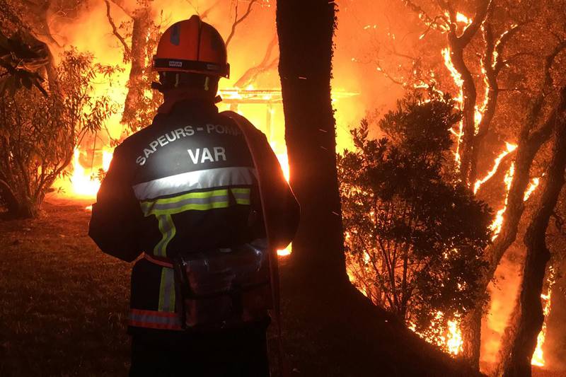 A firefighter tackles flames near Toulon. Hundreds of firefighters battled a wildfire raging through forests inland from the French Riviera.