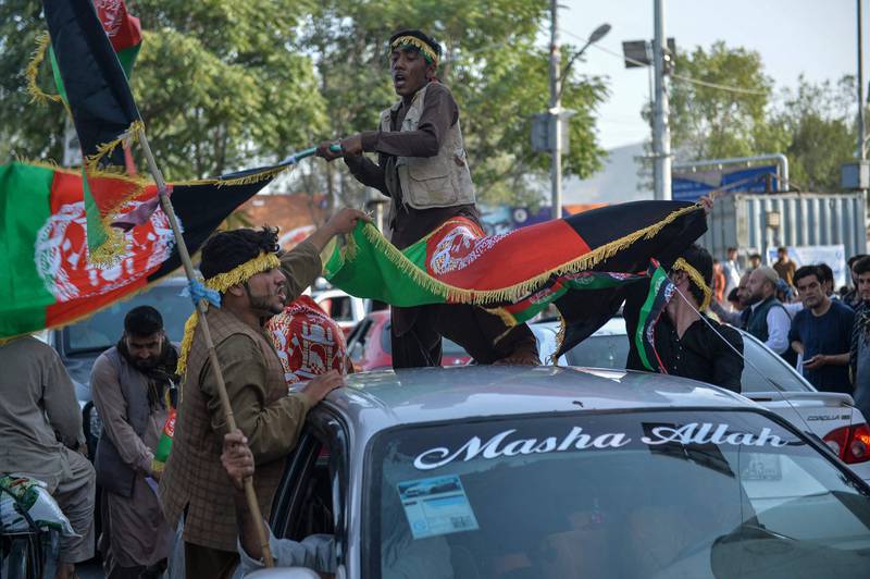 A procession of cars and people carrying Afghan flags makes its way through the streets.   AFP