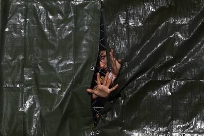 A person gestures through a fence at the immigration processing centre in Manston, Kent in southern England. Reuters