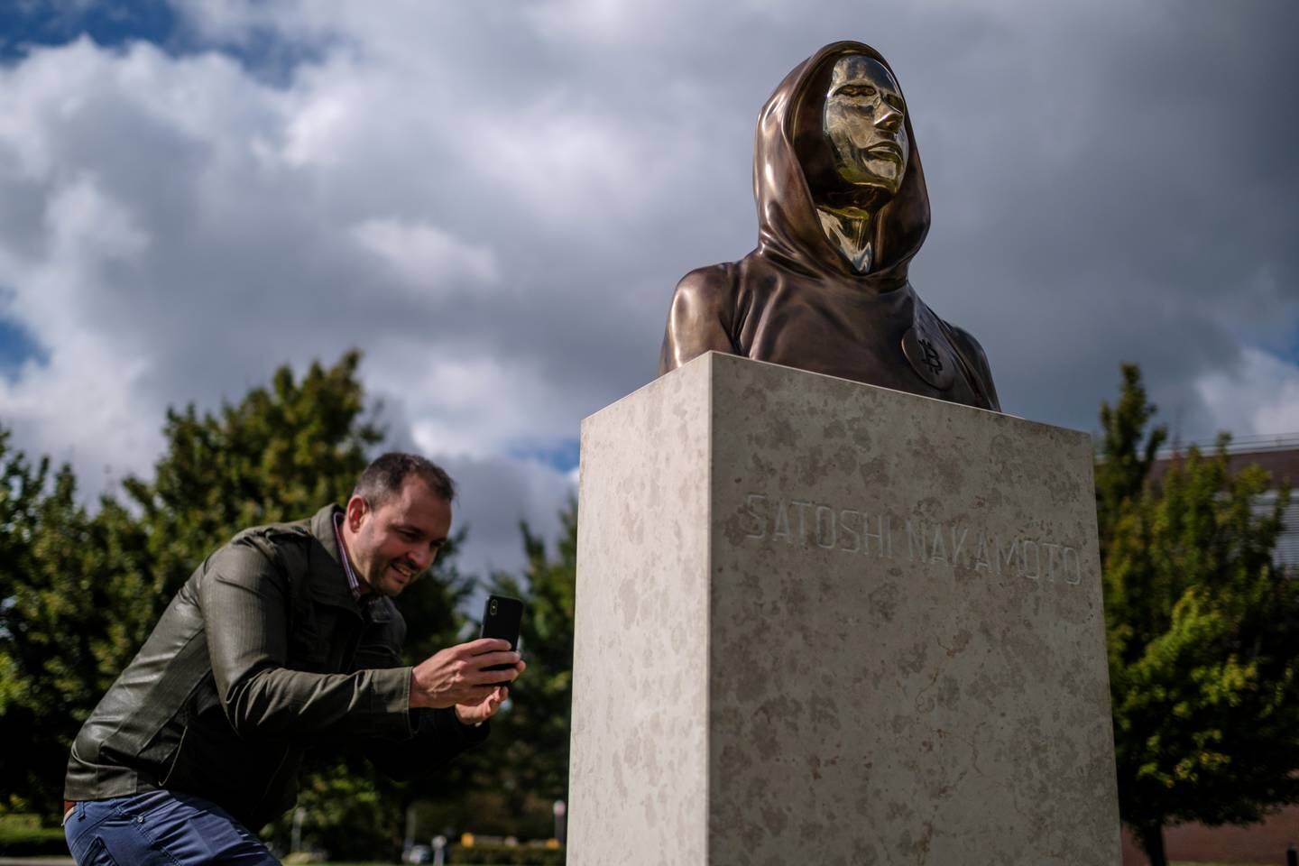 Un passante scatta una foto di una statua di Satoshi Nakamoto a Budapest, in Ungheria.  I creatori della statua, Reka Gergely e Tamas Gilly, hanno utilizzato tratti del viso anonimizzati poiché la vera identità di Nakamoto rimane non confermata.  Getty