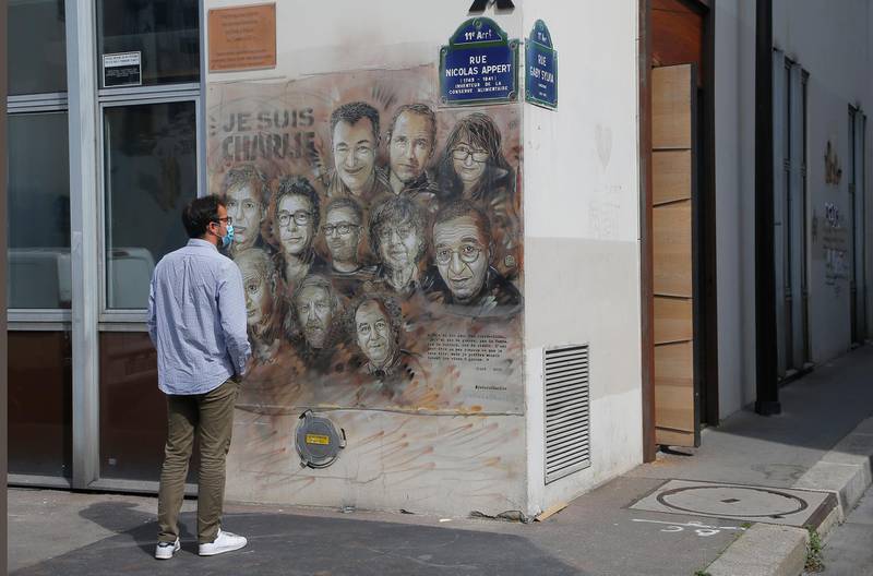 A man wearing a protective face mask as a precaution against the coronavirus looks on a painting by French street artist Christian Guemy, a.k.a. 'C215' in Paris, in tribute to the members of the satirical newspaper Charlie Hebdo attack by jihadist gunmen in January 2015. AP