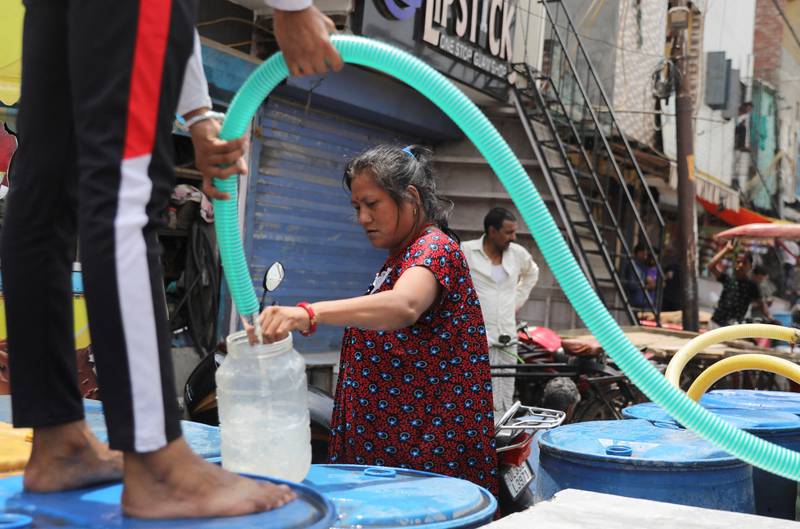 A woman fills a plastic container with drinking water from a municipal tanker in New Delhi. Reuters
