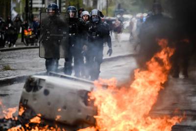 Riot gendarmes walk past a bin in flames in Nantes. AFP